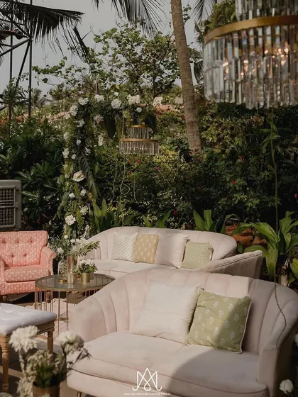 Another view of the pastel lounge seating, with elegant chandeliers hanging from the trees above, creating a magical, garden party atmosphere.