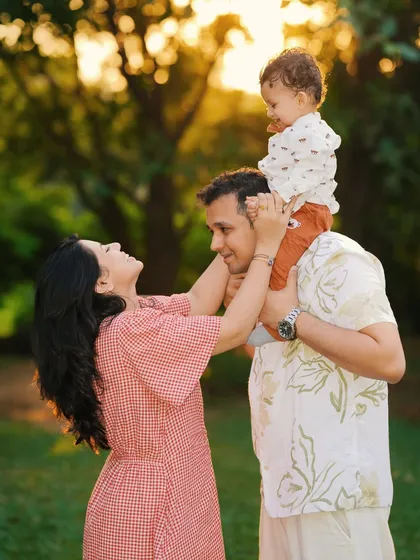 A sweet family interaction during an outdoor session, with the baby sitting on the father's shoulders. These playful moments make for the most authentic portraits.