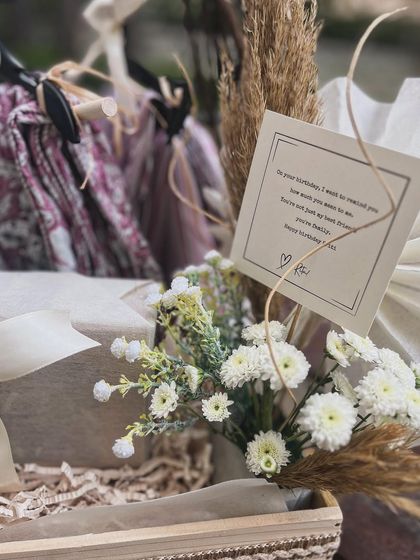 The personal note is always central. Here, it's placed thoughtfully amidst the florals and styled gifts.