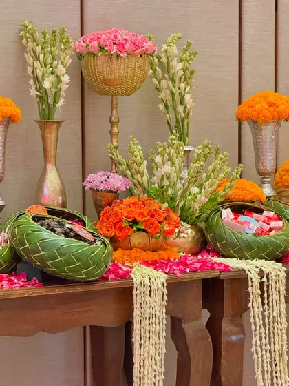 A beautiful display of fresh flowers for a festive celebration. This arrangement includes marigolds, tuberoses, and pink roses in various vases and baskets, creating a fragrant and visually rich corner.