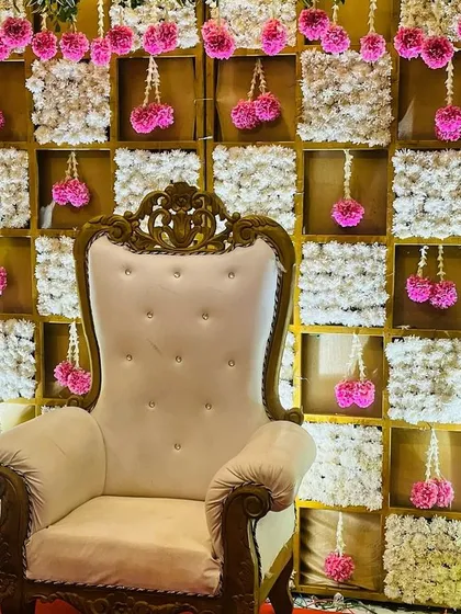 A grid-style backdrop filled with white flowers, with hanging pink floral bunches adding a pop of color.
