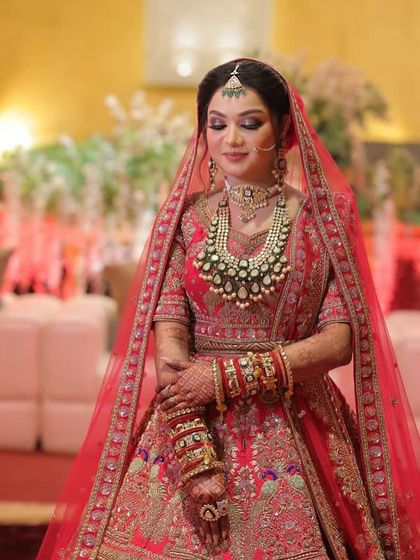 A full view of the bride in her red lehenga. The makeup is classic and timeless, ensuring she will love her wedding photos for years to come.