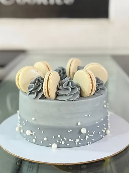 A sophisticated grey cake topped with a circle of classic macarons and sprinkled with pearls.