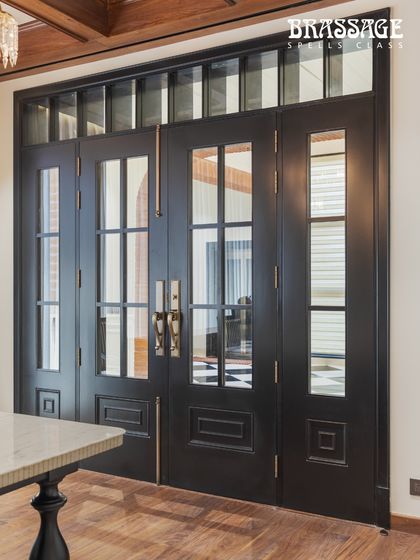 A wide view of the Emperor Door Entrance Set on bold black double doors. The warm Antique Brass Matte finish creates a stunning contrast, highlighting the hardware as a key design element in this luxurious entryway.