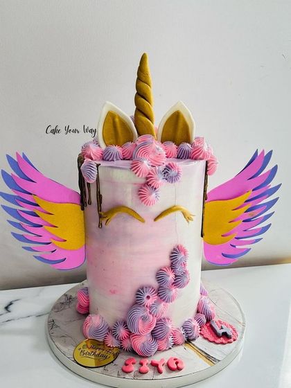 Unicorn magic for a magical birthday. This tall unicorn cake features colorful wings and pretty piped details.