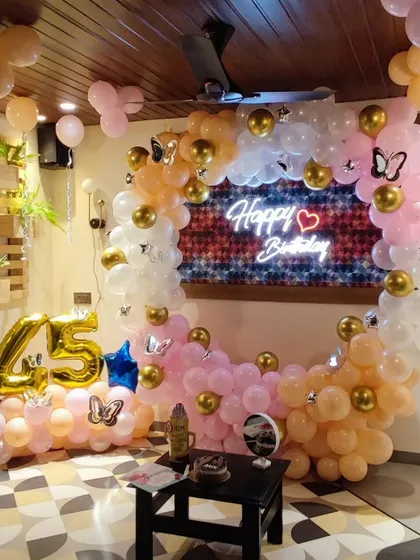 A 45th birthday celebration featuring a circular balloon ring in pastel pink and peach with gold accents. This setup includes large foil numbers and butterfly details, creating a soft and elegant look.