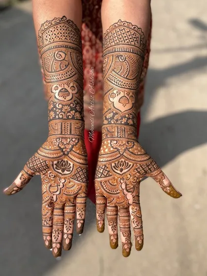 This full-arm bridal mehendi is a beautiful example of traditional Indian artistry. The design includes peacocks, palace architecture, and lotus flowers, all meticulously detailed.