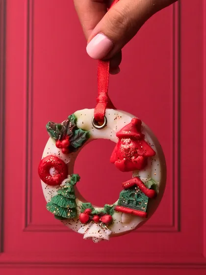 A close-up of my Christmas wreath wax sachet. You can see the tiny, handcrafted details like the Santa hat, house, and trees that make this piece so special.