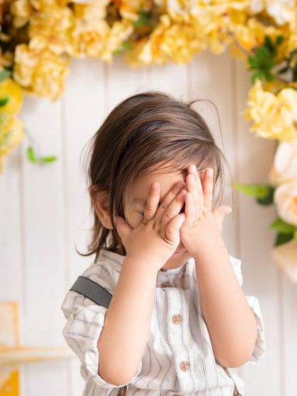 A cute game of peek-a-boo! I love capturing these playful, candid moments that show off your child's personality.