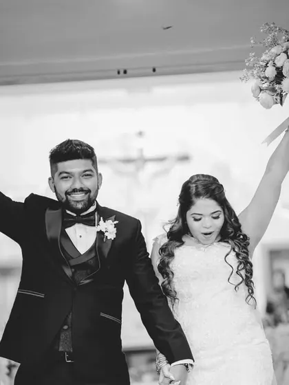 A triumphant and joyful black and white photo of the couple exiting the church, cheered on by their loved ones. Their raised arms and happy faces tell a story of celebration.