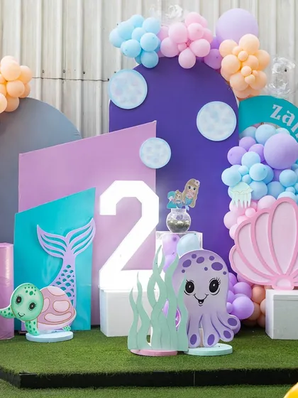 A beautiful "Under the Sea" backdrop for Zaira's 2nd birthday. The combination of pastels, a light-up number, and adorable sea creatures creates a picture-perfect setting.