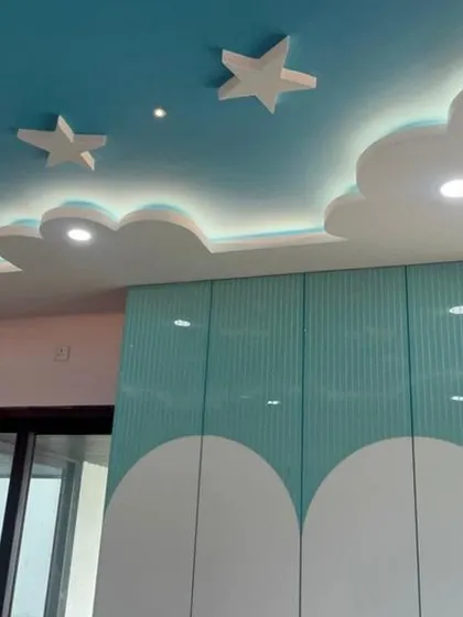 Another angle of our cloud-themed kids' room, showing the custom wardrobe with curved, two-tone doors that complement the whimsical ceiling design.