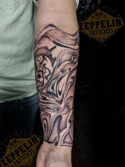 A close-up of the upper part of "The Chaos" sleeve, where a hidden face emerges from the fluid design.