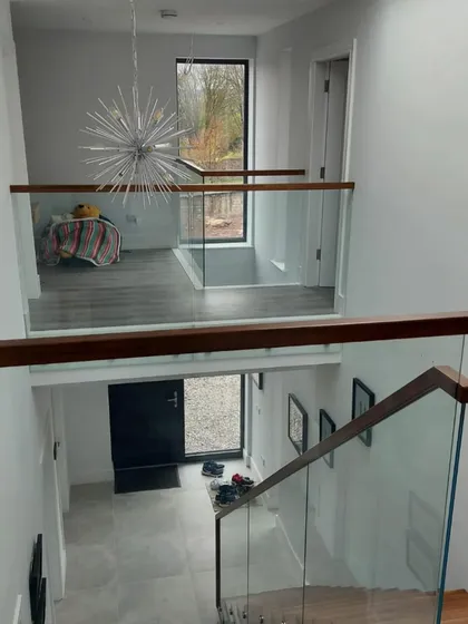 A look down into the entryway from the mezzanine landing. The glass balustrade provides safety without creating a visual barrier.