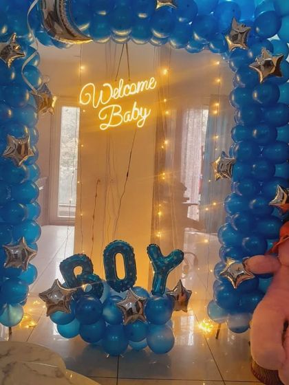 A closer look at the "Welcome Baby Boy" balloon arch, showing the teddy bear and fairy light details.