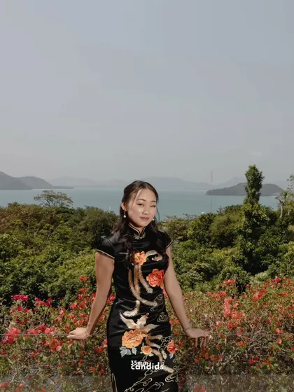 The bride, Aline, in a traditional Chinese Qipao, stands against the lush Phuket landscape. This portrait honors her heritage before she embraces the traditions of her new family.