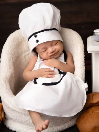 Meet the little chef. A sleeping newborn dressed in a chef's hat and apron, looking perfectly content after a busy "day" in the kitchen.