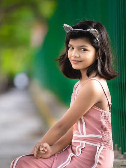 A simple and sweet outdoor portrait. The natural green background makes the subject stand out, and the relaxed pose captures her calm and gentle personality.