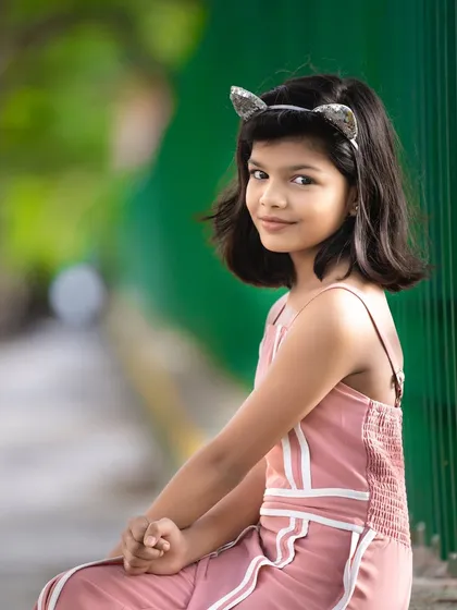 A simple and sweet outdoor portrait. The natural green background makes the subject stand out, and the relaxed pose captures her calm and gentle personality.