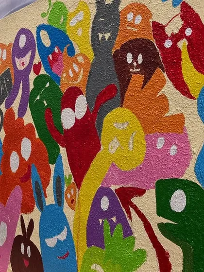 The process of filling in the doodle mural, showing how each monster is individually painted to create a dense and energetic composition.
