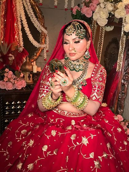 The bride's final check in the mirror. This look highlights the rich red and gold embroidery of the lehenga with makeup that is equally detailed and luxurious.
