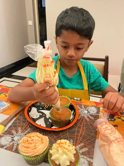 The concentration is real. This young baker is mastering the art of piping frosting onto his Halloween-themed cupcakes, all made from scratch.
