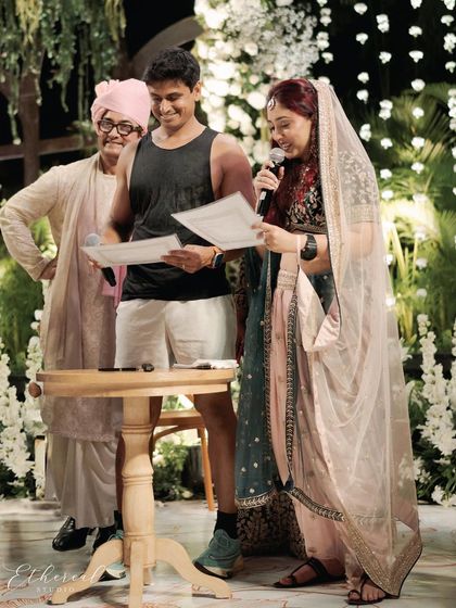A wider shot of the signing ceremony, with the bride's father looking on with a smile. This image captures the blend of tradition and personality that defined their wedding.