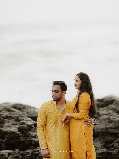 A moody and romantic portrait of the couple on a rocky shore, their figures standing out against the dramatic seascape.