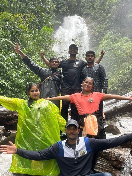 A group of friends with arms outstretched, enjoying the refreshing spray of Hidlumane Falls.