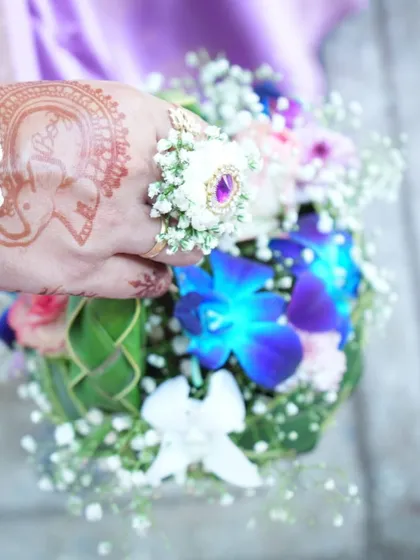 A close-up on the hand of a mom-to-be, showing a delicate floral ring and the matching woven basket filled with colorful flowers.