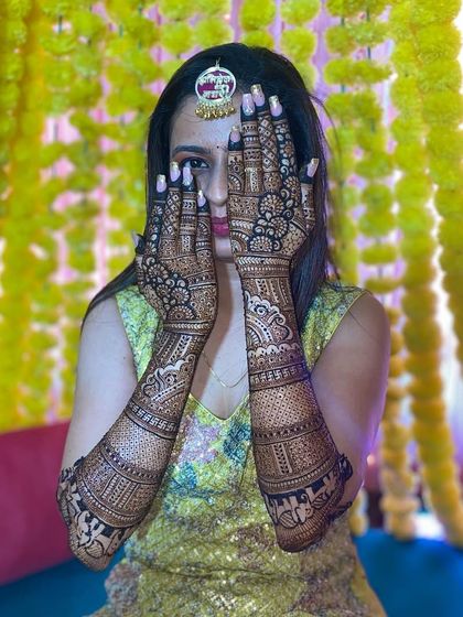 Another beautiful shot of the bride and her intricate mehandi, set against a festive backdrop of marigold flowers.