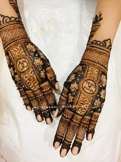 A personalized engagement design featuring the couple's names, 'Tejas & Pooja', inside a central motif. The other hand showcases interlocking rings, surrounded by beautiful lotus patterns.