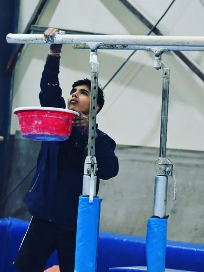 A student prepares the parallel bars with chalk, getting ready for his training session.