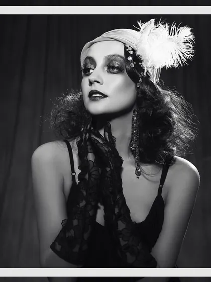 Recreating the iconic glamour of the Roaring Twenties for a 'Great Gatsby' themed shoot. This look features a classic flapper-style headpiece with feathers, delicate lace gloves, and period-appropriate lingerie to transport the viewer back to 1925.