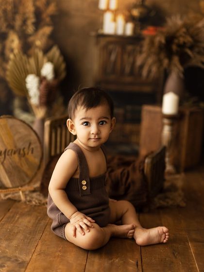A similar pose from a different angle, showing the baby's sweet expression as they sit on the wooden floor.