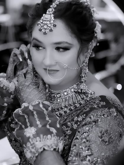A black and white shot of the bride getting ready, seen through the reflection of a ring light. This creative framing adds a modern touch to a classic behind-the-scenes moment.