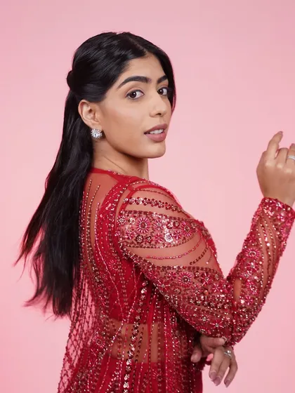 A close-up of the red three-piece Indo-Western set, highlighting the detailed embroidery on the sheer jacket.