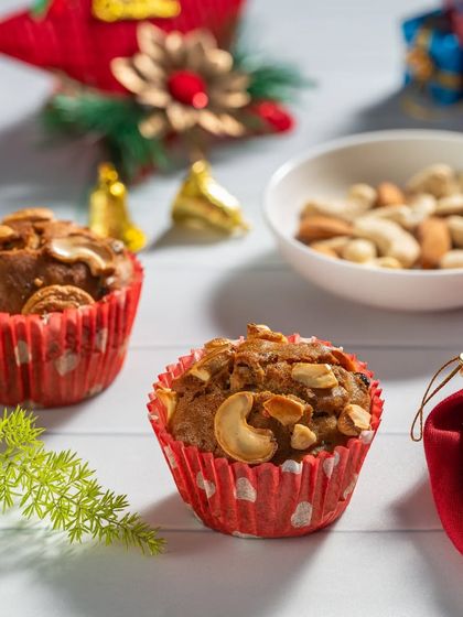 Cashew-topped muffins in festive red polka-dot wrappers, perfect for a holiday bakery promotion.
