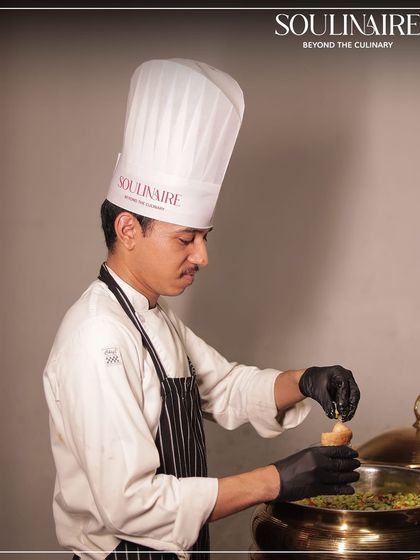 A chef carefully assembling a dish at a live station during an exquisitely curated sit-down dinner in Ahmedabad. Every plate is a tribute to thoughtful craft.