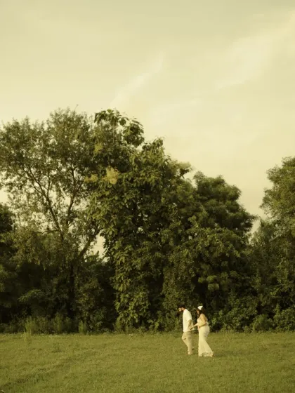 A simple walk in nature becomes a profound symbol of the journey ahead. This wide-angle shot shows the couple in a vast green field, emphasizing the path they are taking together.