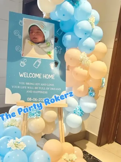 A personalized welcome sign for the baby's arrival, featuring a newborn photo and surrounded by a pastel balloon garland.