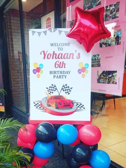 A personalized welcome sign for a racing cars themed 6th birthday party, set up at the entrance of a Burger King.