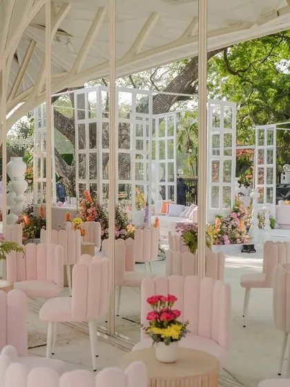 Modern and whimsical seating for the "Bloom" wedding. The unique, shell-backed pink chairs are arranged in a beautiful glasshouse-like structure, creating a light and airy lounge space for guests.