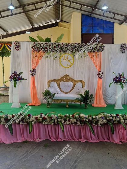 A beautiful stage setup for an engagement or reception, with a sofa, floral arrangements, and elegant draping.