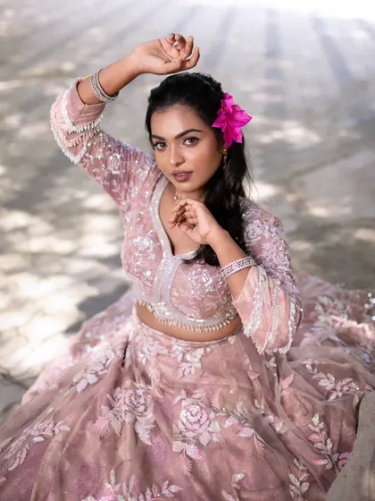 A model posing with a pink flower in her hair, adding a touch of playfulness to her glamorous look.