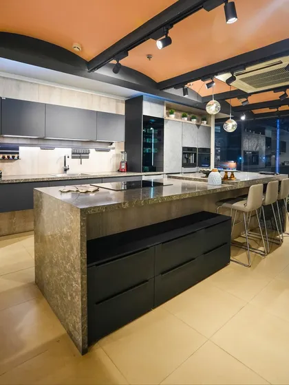 This dramatic display in our Kolkata showroom features a large island with a stone-look finish and an integrated bench, showcasing a monolithic and architectural design.
