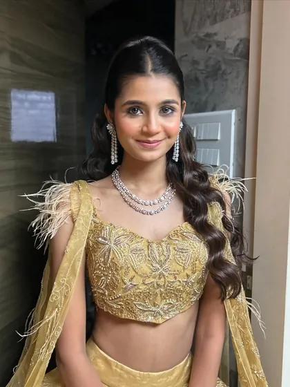 A glamorous look for a party. The client is wearing a gold lehenga, and her makeup is shimmery and defined.