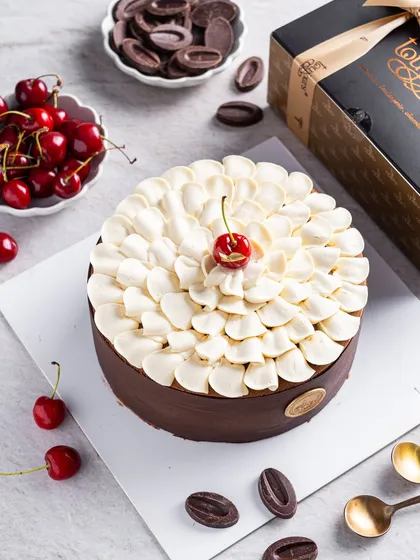 Our modern take on the Black Forest cake, topped with a cloud of vanilla namelaka and a single fresh cherry. This entremet is a complex assembly of chocolate, cherry, and cream, perfect for a refined palate.