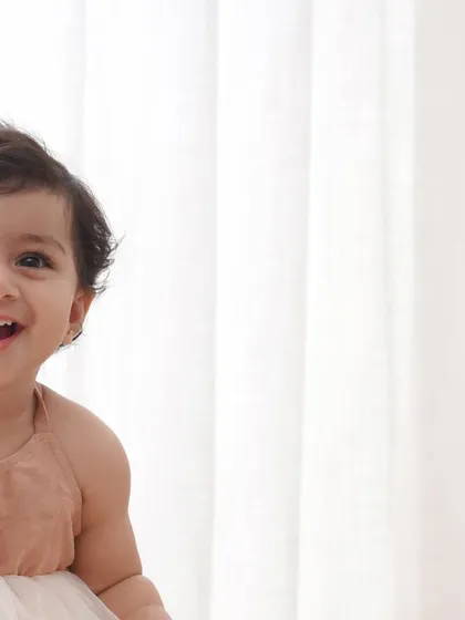 A joyful, laughing baby girl captured in a candid moment during her first birthday photoshoot.