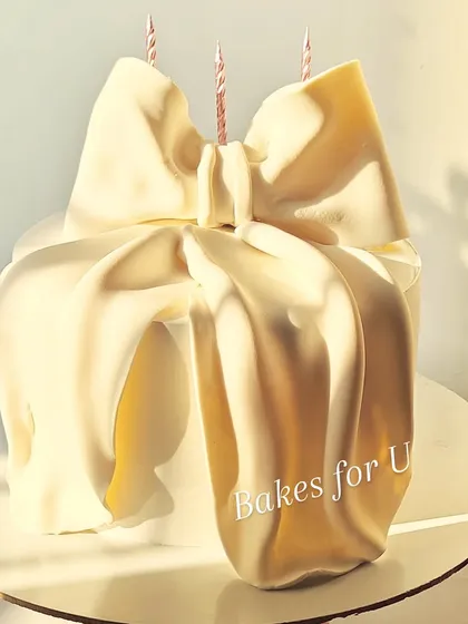 A chic and modern bow cake, where the entire gift box look is created with draped white chocolate. This elegant and trendy design is perfect for a fashion-forward celebration.
